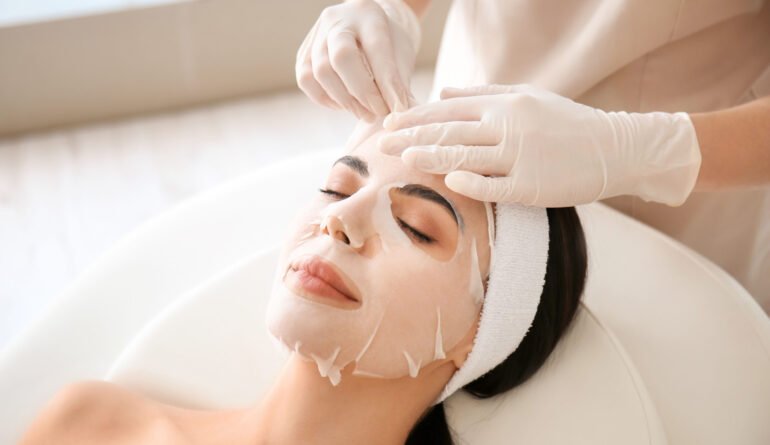 Cosmetologist applying sheet mask on woman's face in beauty salon Cosmetologist applying sheet mask on woman's face in beauty salon